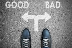 A pair of feet faced with a choice: do good or do bad, which are noted on the ground in front of the feet